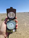 Person is holding a compass outdoors in a desert landscape