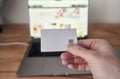 Person holds credit card in front of computer for online transaction Royalty Free Stock Photo