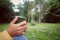 Closeup of woman sitting relax on park, hands holding cup of tea or coffee.