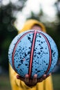 An unrecognizable person is playing with a colorful basketball on the street