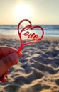 Person holding fingers hand stick shape red heart and word Love background sea Royalty Free Stock Photo