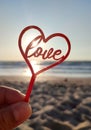 Person holding fingers hand stick shape red heart and word Love background sea Royalty Free Stock Photo