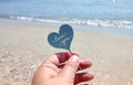 Person holding in fingers plastic stick in shape heart and words Love you