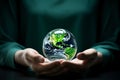 A person is holding a globe in their hands. The globe is made of glass and is green Royalty Free Stock Photo