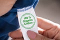 Person Holding Label Showing 100 Percent Organic Cotton