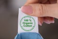 Person Holding Label Showing 100 Percent Organic Cotton