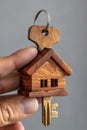 A person holding a miniature house keychain with two keys, AI