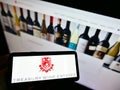 Person holding mobile phone with business logo of Australian winemaking company Treasury Wine Estates on screen with website. Royalty Free Stock Photo