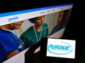 Person holding mobile phone with business logo of US pharmaceuticals company Purdue Pharma LP on screen in front of web page. Royalty Free Stock Photo