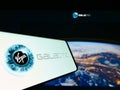 Person holding mobile phone with logo of American aerospace company Virgin Galactic LLC on screen in front of web page.