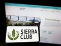 Person holding mobile phone with logo of American environmental organization Sierra Club on screen in front of web page.