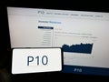 Person holding mobile phone with logo of American investment company P10 Holdings Inc. on screen in front of web page. Royalty Free Stock Photo