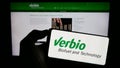 Person holding mobile phone with logo of biofuel company Verbio Vereinigte Bioenergie AG on screen in front of web page. Royalty Free Stock Photo