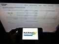Person holding mobile phone with logo of biotechnology company WuXi Biologics (Cayman) Inc. on screen with web page.