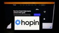 Person holding mobile phone with logo of British event management company Hopin Ltd. on screen in front of web page.