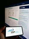 Person holding mobile phone with logo of British foodservice company SSP Group plc on screen in front of web page with chart. Royalty Free Stock Photo
