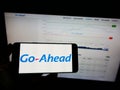 Person holding mobile phone with logo of British transport company The Go-Ahead Group plc on screen in front of web page.