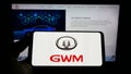 Person holding mobile phone with logo of car manufacturer Great Wall Motors Co. Ltd. (GWM) on screen with web page.