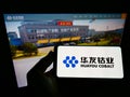Person holding mobile phone with logo of Chinese mining company Huayou Cobalt Co. Ltd. on screen in front of web page.