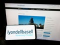 Person holding mobile phone with logo of company LyondellBasell Industries NV on screen with webpage