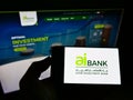 Person holding mobile phone with logo of financial company Arab Investment Bank (AIB Egypt) on screen with web page.