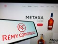 Person holding mobile phone with logo of French spirits company RÃÂ©my Cointreau on screen in front of website. Royalty Free Stock Photo