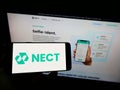 Person holding mobile phone with logo of German identity verification company Nect GmbH on screen in front of web page. Royalty Free Stock Photo