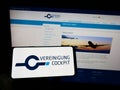 Person holding mobile phone with logo of German pilot association Vereinigung Cockpit on screen in front of web page.