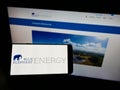 Person holding mobile phone with logo of German solar energy company Blue Elephant Energy AG on screen in front of webpage.