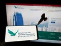 Person holding mobile phone with logo of Hong Kong Securities and Futures Commission (SFC) on screen with web page.