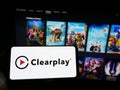 Person holding mobile phone with logo of parental control company Clearplay Inc. on screen in front of business web page.