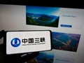 Person holding mobile phone with logo of power company China Three Gorges Corporation (CTG) on screen with web page.