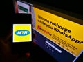 Person holding mobile phone with logo of South African telecommunications company MTN Group on screen in front of web page. Royalty Free Stock Photo