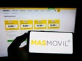 Person holding mobile phone with logo of Spanish MÃÂ¡sMÃÂ³vil Ibercom S.A. (Grupo MasMovil) on screen with web page. Royalty Free Stock Photo