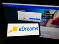 Person holding mobile phone with logo of Spanish online travel agency Vacaciones eDreams S. L on screen in front of web page.