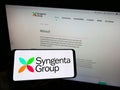 Person holding mobile phone with logo of Swiss agriculture company Syngenta Group on screen in front of business web page. Royalty Free Stock Photo