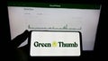 Person holding mobile phone with logo of US cannabis company Green Thumb Industries Inc. on screen in front of web page. Royalty Free Stock Photo