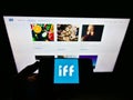 Person holding mobile phone with logo of US company International Flavors and Fragrances (IFF) on screen with webpage.