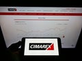Person holding mobile phone with logo of US hydrocarbon exploration company Cimarex Energy Co. on screen in front of webpage.