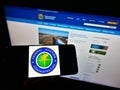 Person holding mobile phone with seal of American agency Federal Aviation Administration (FAA) on screen with webpage.