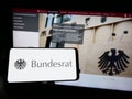 Person holding mobile phone with seal of German legislative body Bundesrat on screen in front of web page.