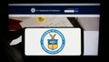 Person holding mobile phone with seal of the United States Department of Commerce (DOC) on screen in front of web page. Royalty Free Stock Photo