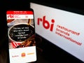 Person holding mobile phone with web page of food company Restaurant Brands International (RBI) on screen with logo.