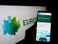 Person holding mobile phone with webpage of financial services company Euronext N.V. on screen in front of logo.