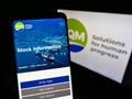 Person holding mobile phone with website of company Sociedad QuÃÂ­mica y Minera de Chile (SQM) on screen with logo.