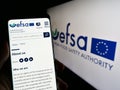 Person holding mobile phone with website of EU agency European Food Safety Authority (EFSA) on screen with logo.