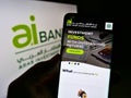 Person holding mobile phone with website of financial company Arab Investment Bank (AIB Egypt) on screen with logo