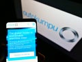 Person holding mobile phone with website of Finnish steel producer Outokumpu Oyj on screen in front of logo.