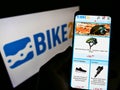 Person holding mobile phone with website of German bicycle e-commerce company Bike24 GmbH on screen with logo.