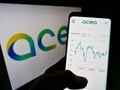 Person holding mobile phone with website of Italian utility company Acea S.p.A. on screen in front of logo.